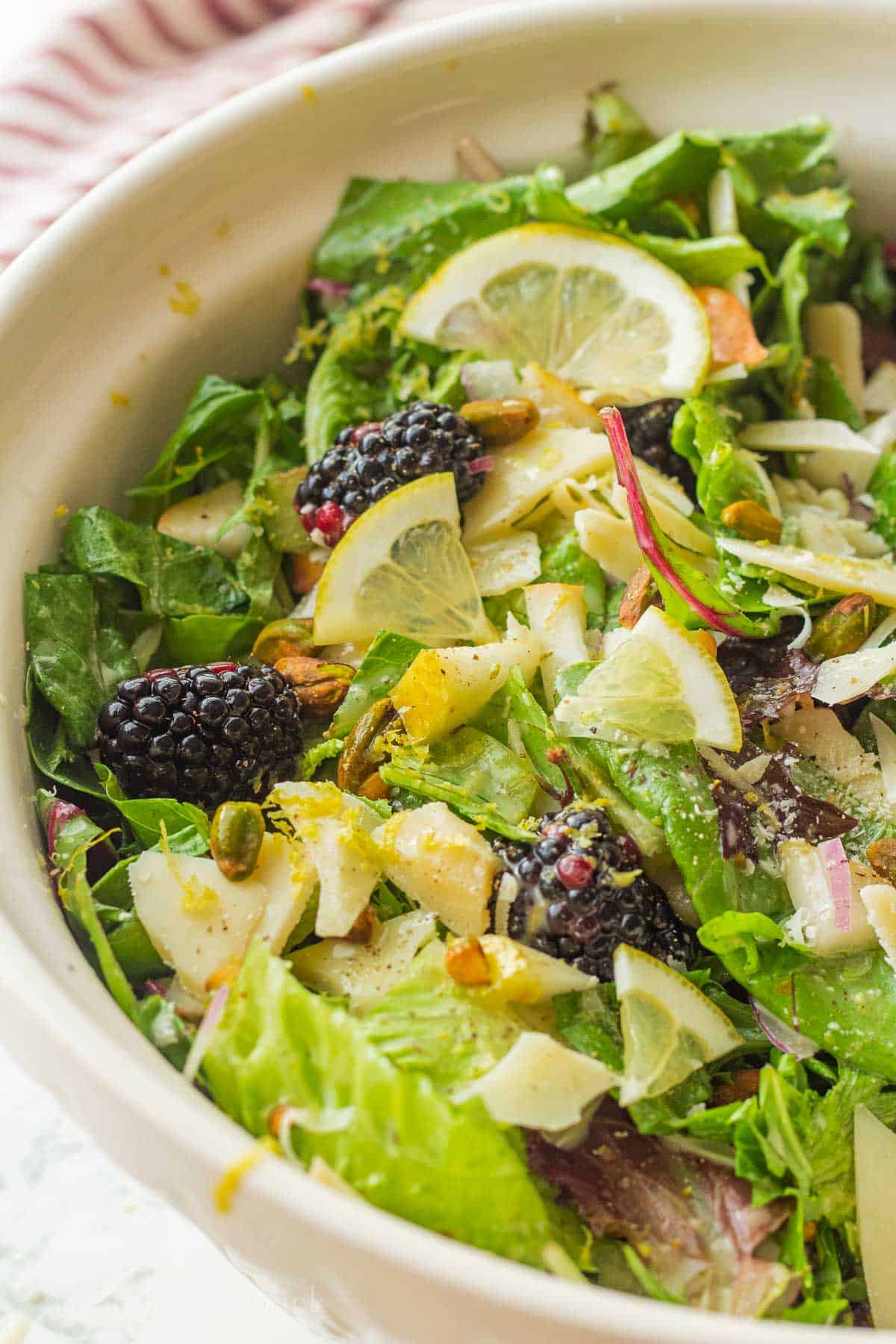 Edible lemon slices, pears, and blackberries on salad.