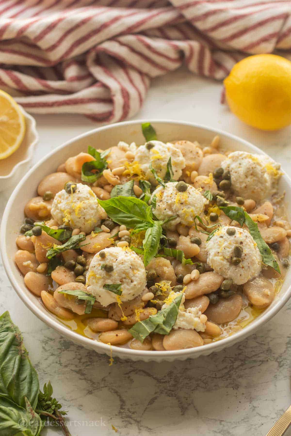 Butter bean salad with ricotta in bowl with basil.