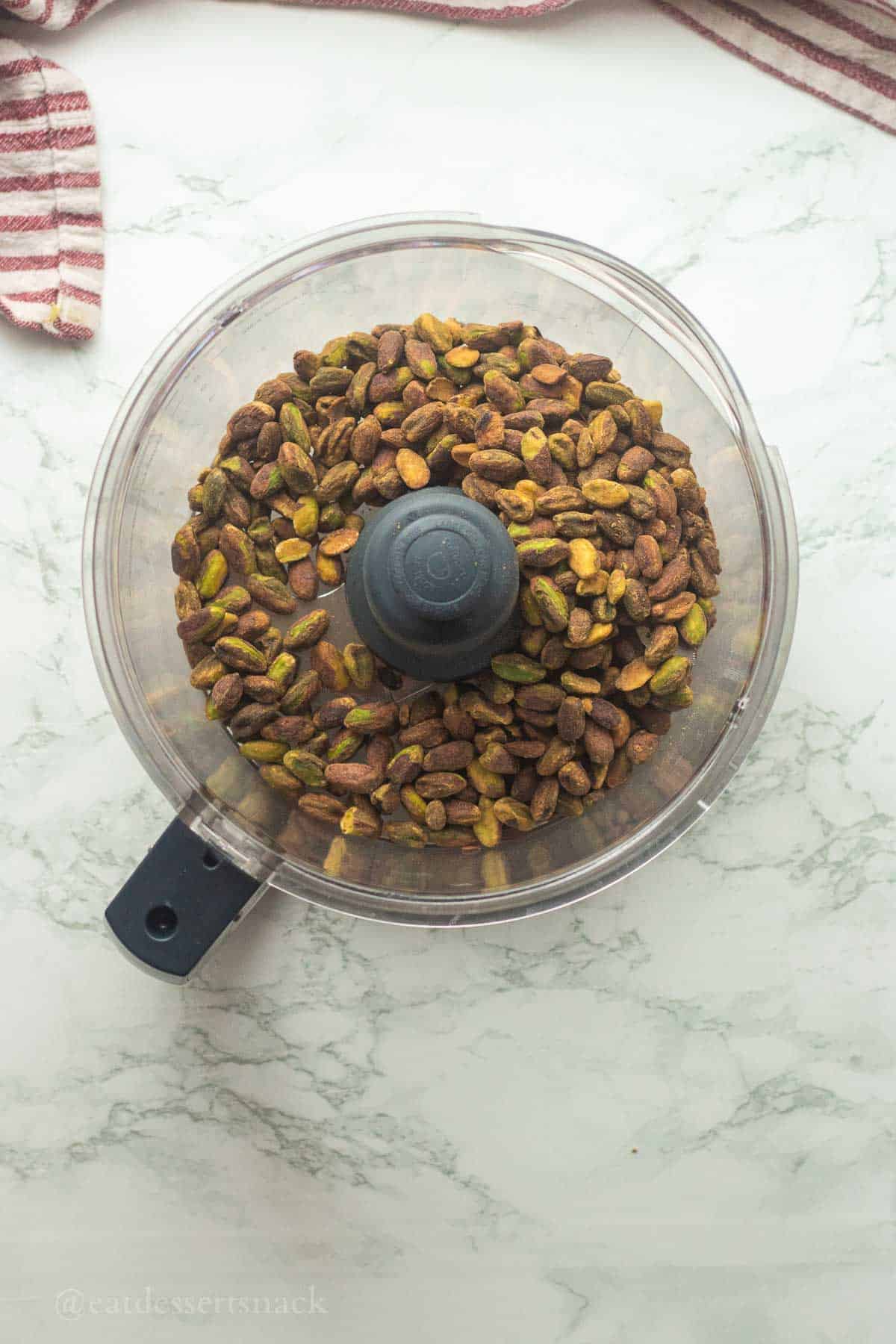 Pistachios in bowl of food processor.