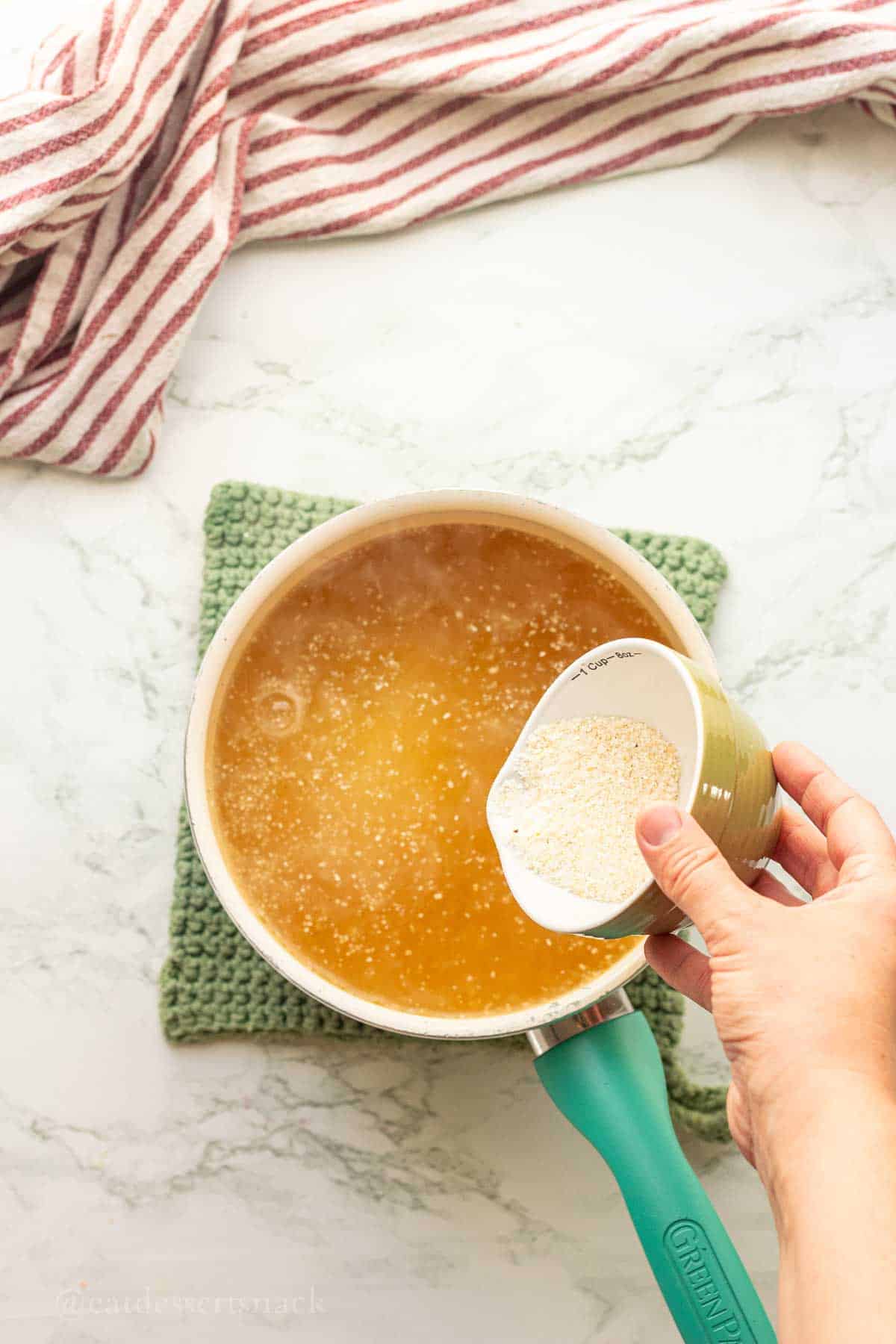 Pouring grits into pot of chicken broth.