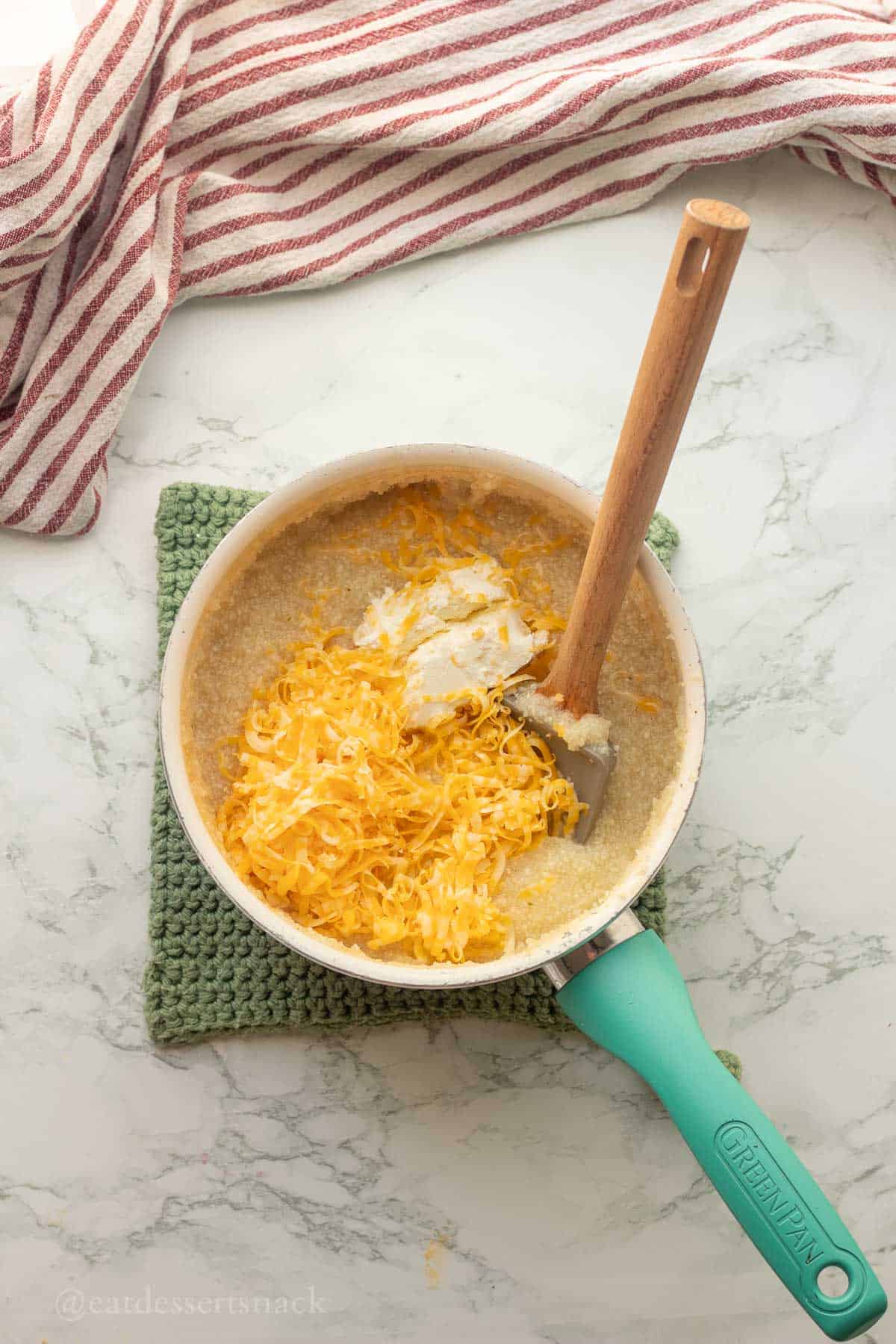 Cheddar cheese and cream cheese in pan of grits.