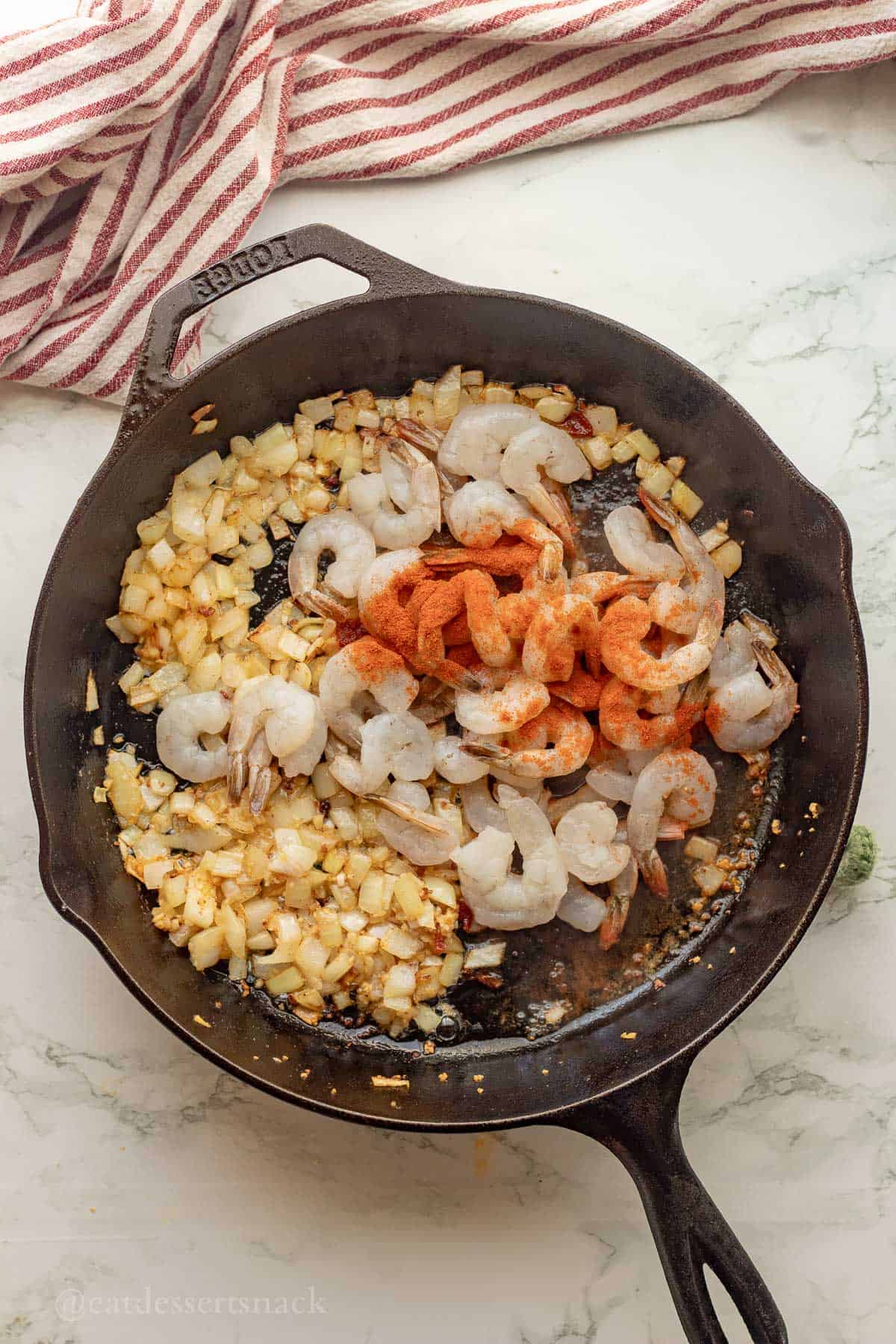 Cooking shrimp in frying pan with onions.