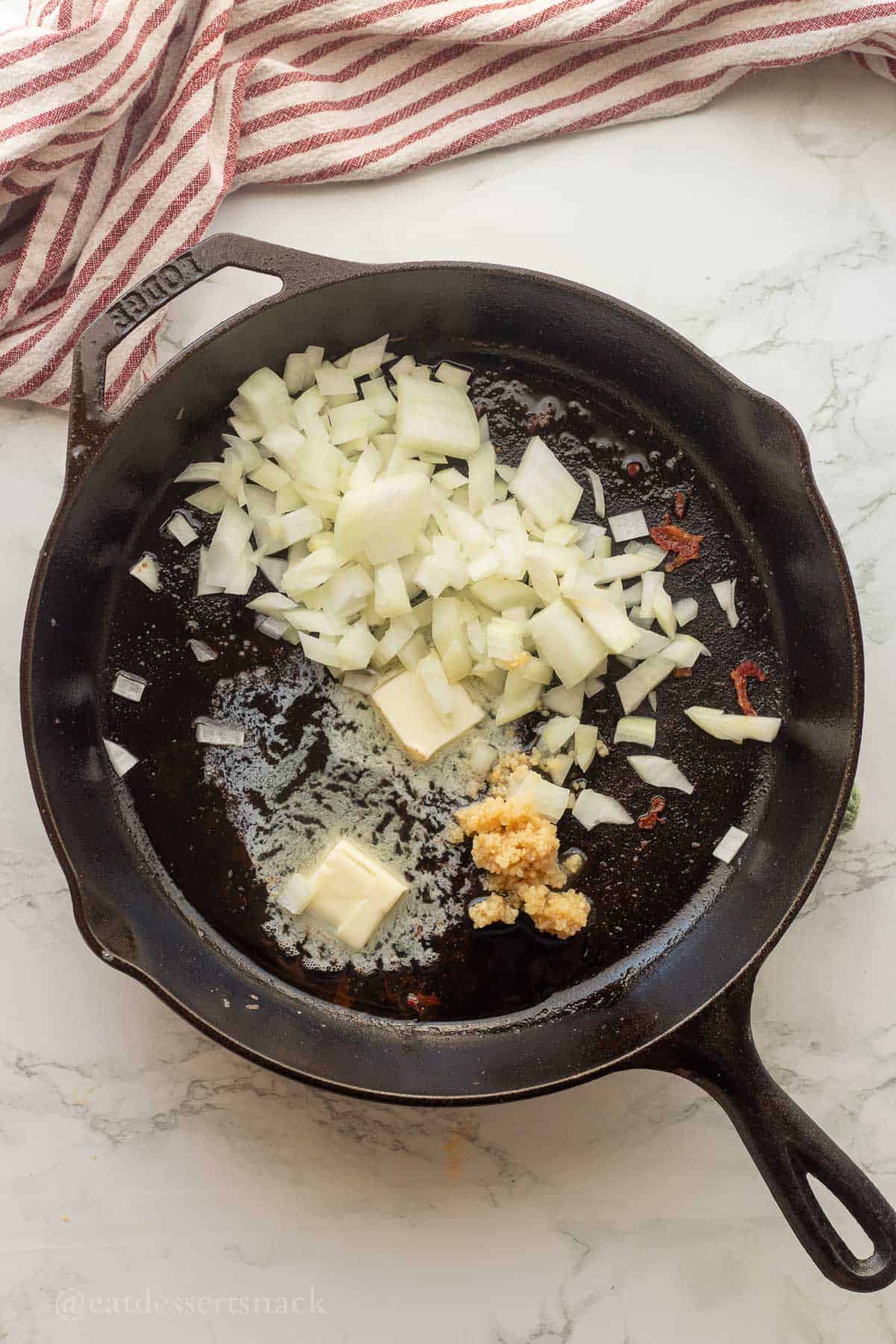 Cooking onions with butter and garlic in frying pan.