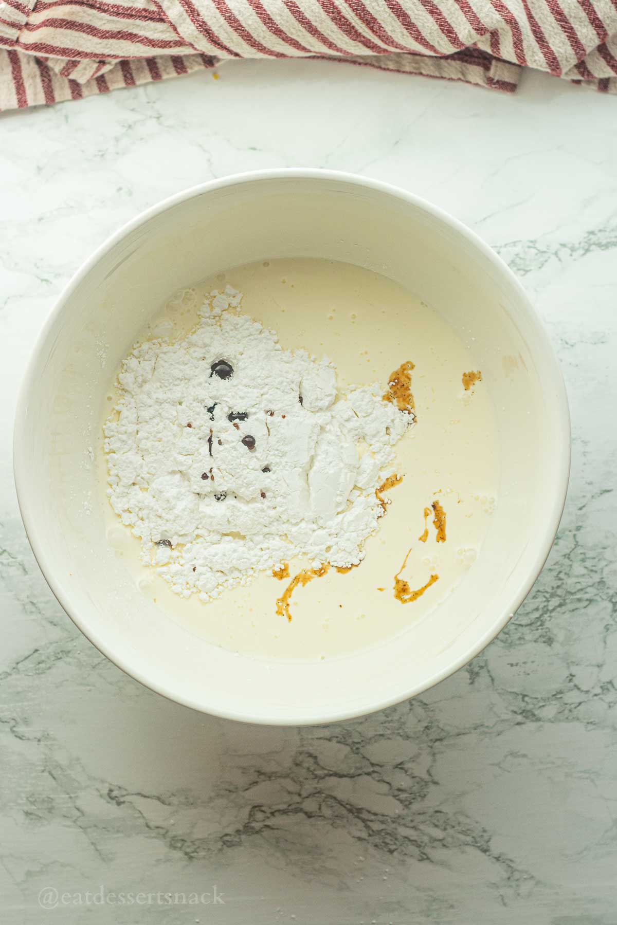 Powdered sugar and vanilla in bowl of cream.