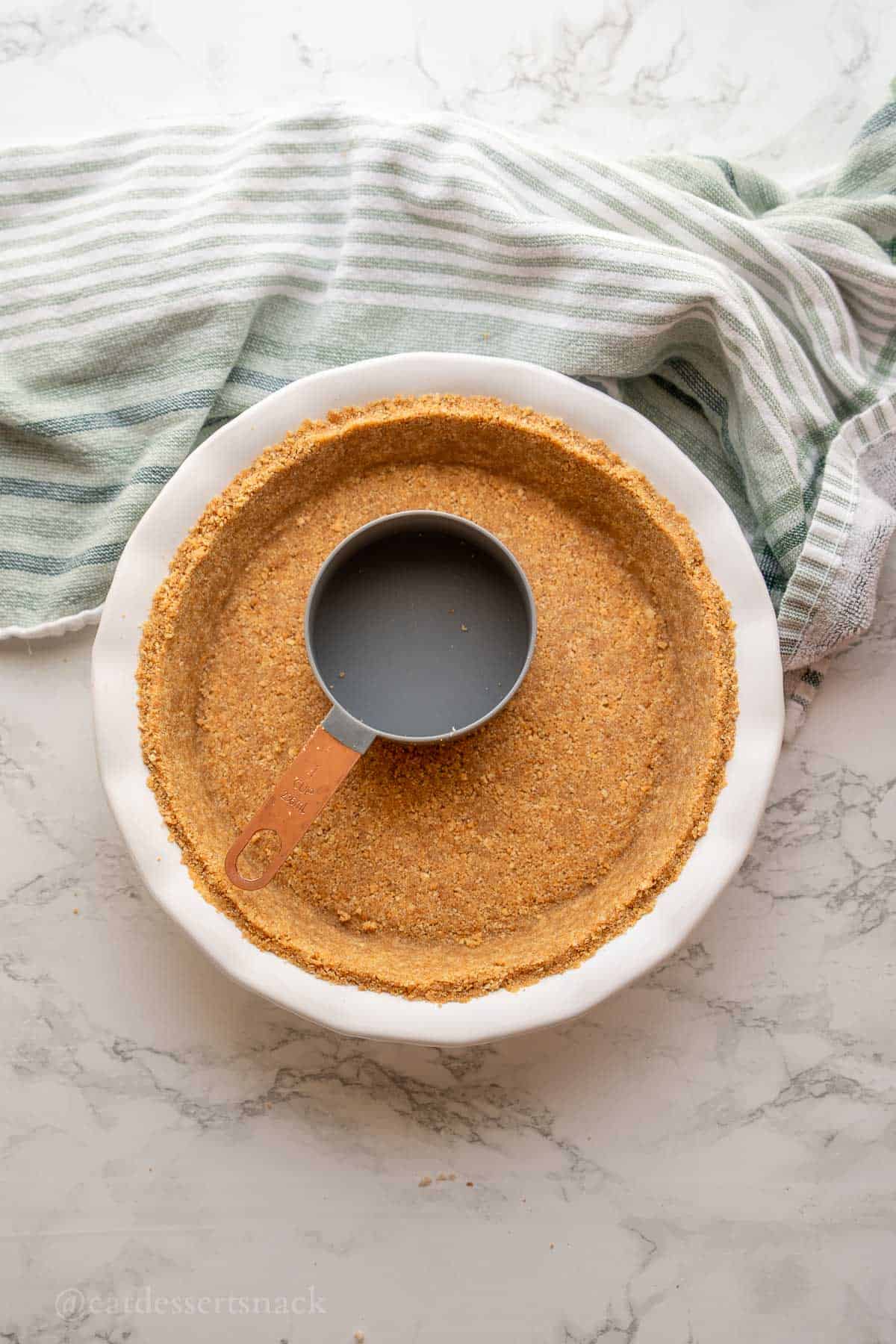 Pressing measuring cup into graham cracker crust.