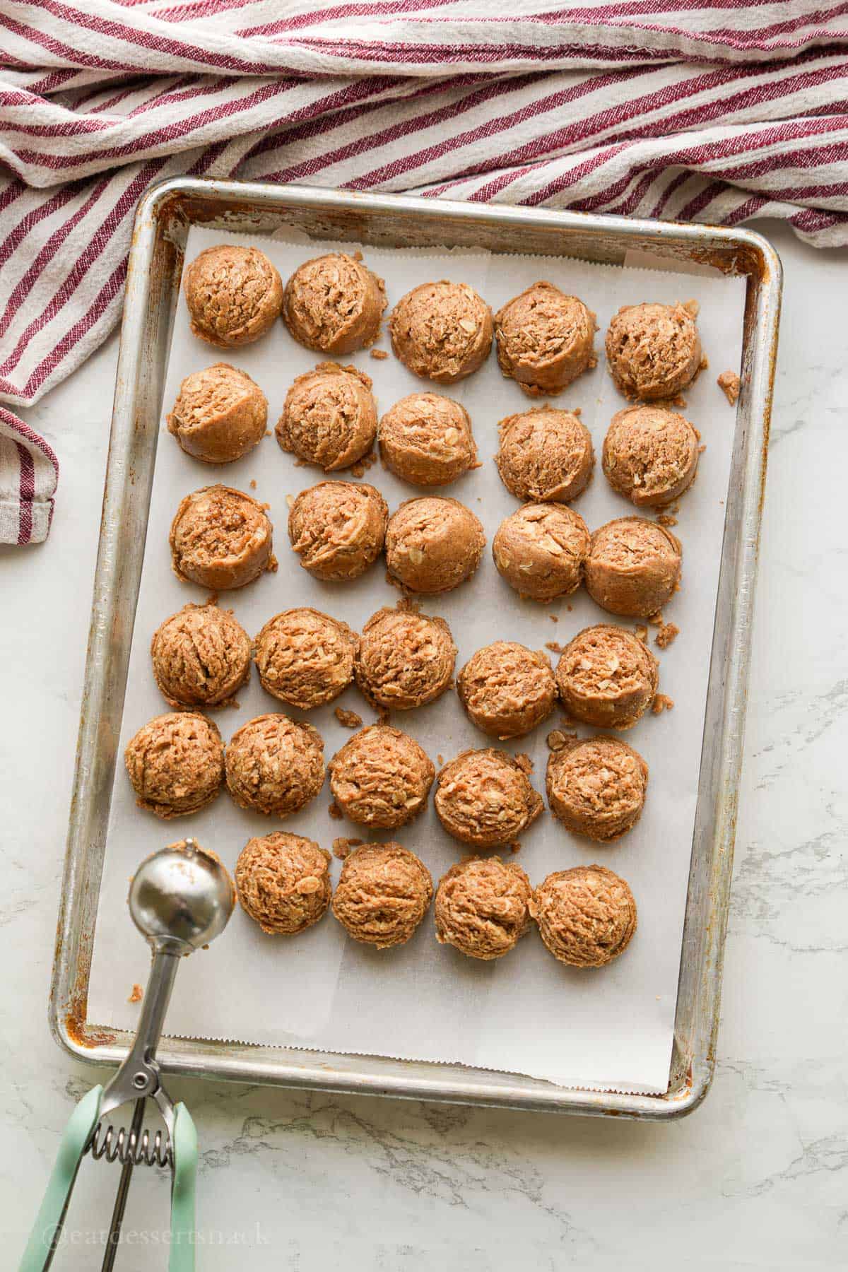 Scooping almond butter bites onto baking sheet.