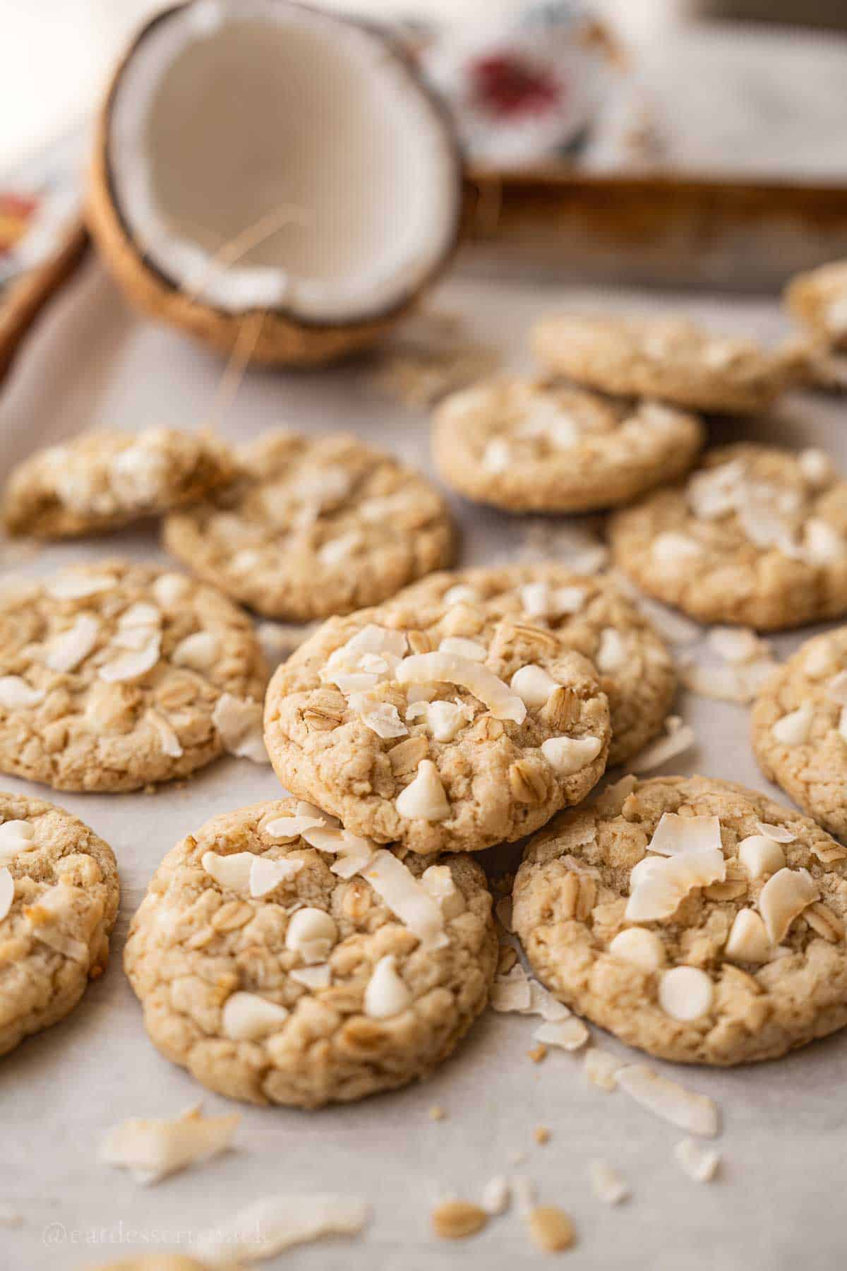 Baked coconut oatmeal cookies on tray with coconut half.