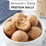 Bite out of almond date protein balls in bowl.