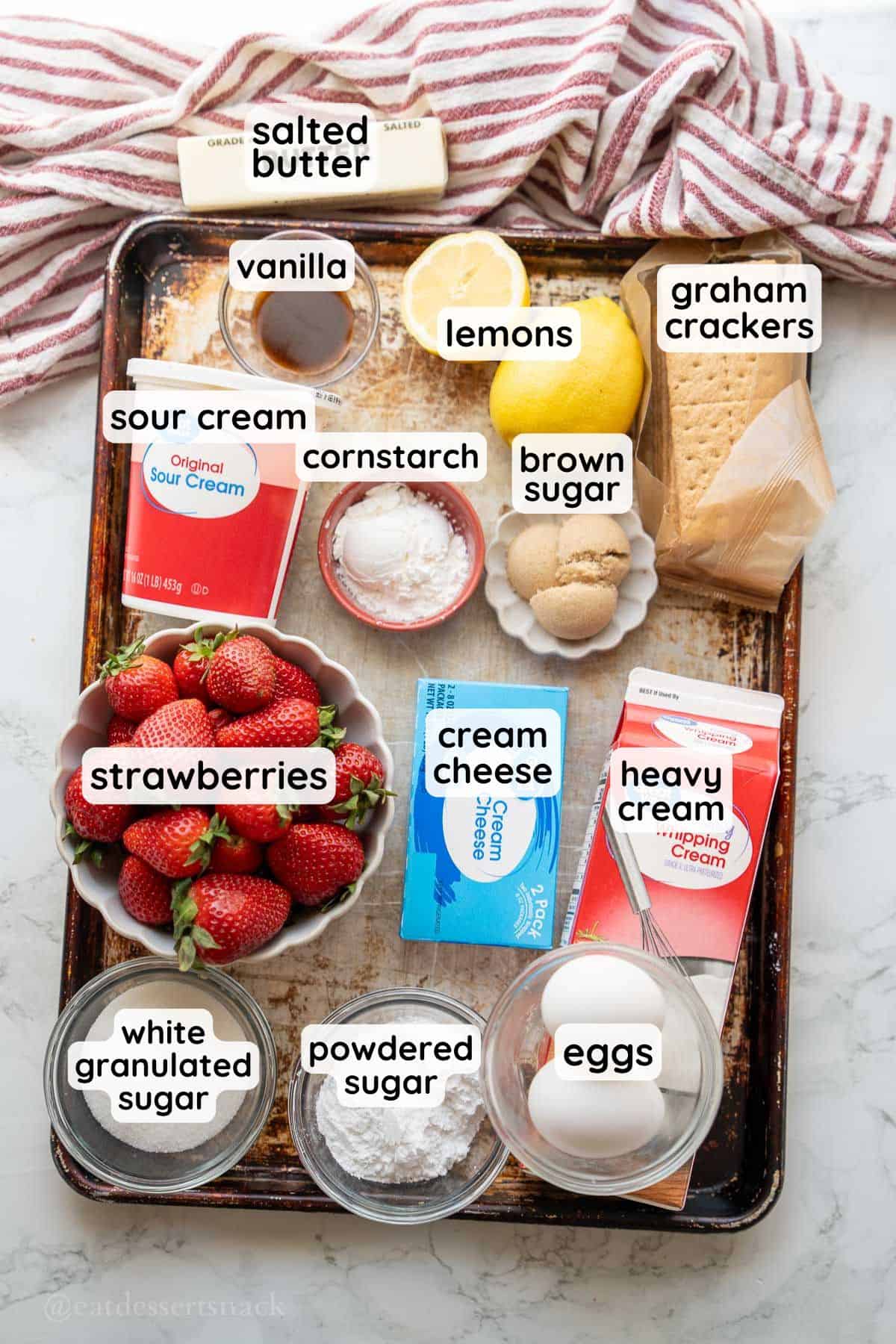 Labeled ingredients for strawberry cream pie on metal baking tray.