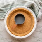 Smoothing graham cracker crust with cup.