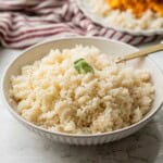 Cooked jasmine rice with gold spoon in bowl.