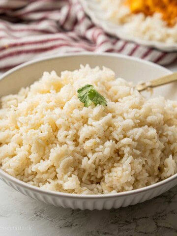 Cooked jasmine rice with gold spoon in bowl.