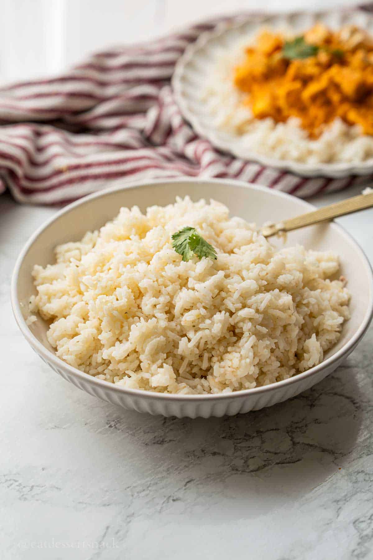 Cooked jasmine rice with gold spoon in bowl.