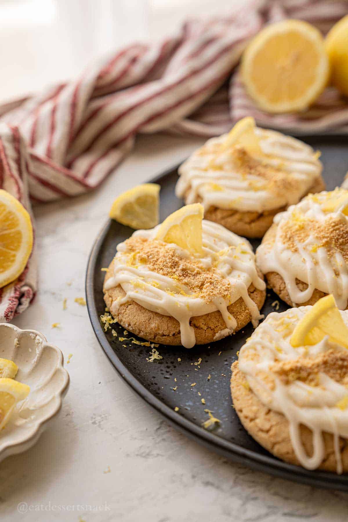 Lemon cheesecake cookie baked on plate with lemon wedges.